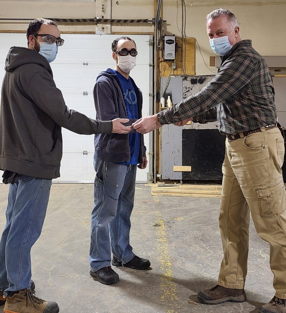 Woods and Plastics Chrysalis employees receiving their HSE challenge coin from the HSE coordinator